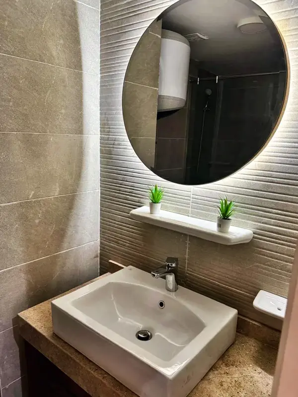 Stone basin under a round backlit mirror
