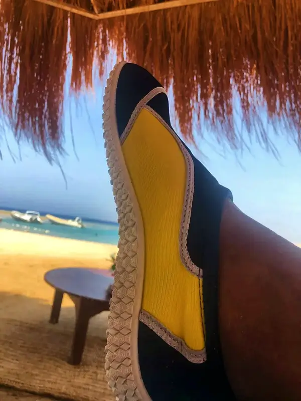 Fins and a lounger in the shade of a beach parasol