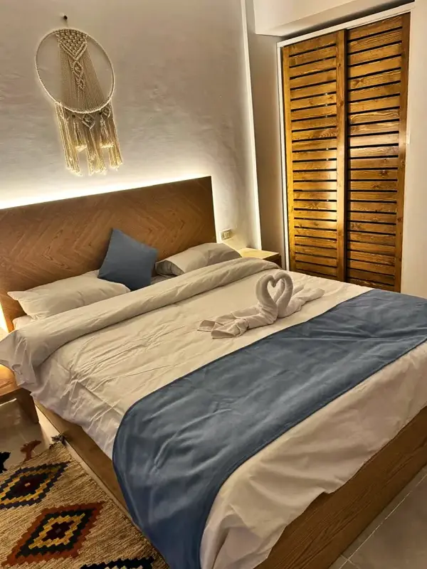 Double bed made up with towel swans, louvred wardrobe behind