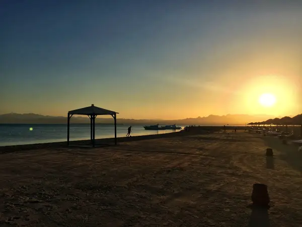 A gazebo on the sand at sunset